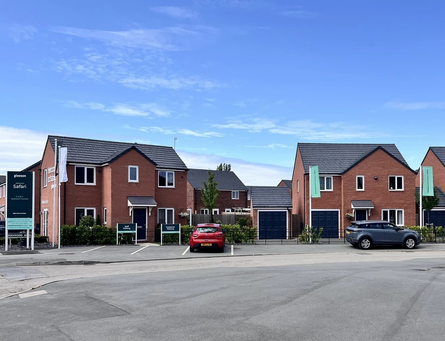 A picture of some new build red brick houses under blue skies.