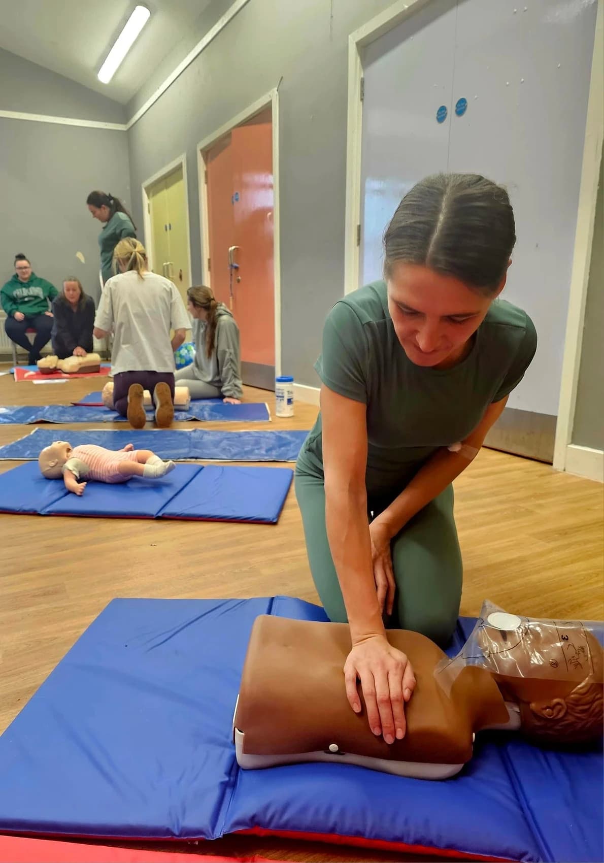 A picture of local community members doing a 1st aid course on dummies in the community centre.