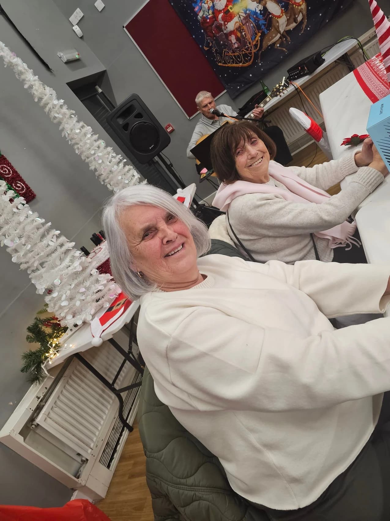 A picture of two women enjoying a Christmas lunch with live entertainment.