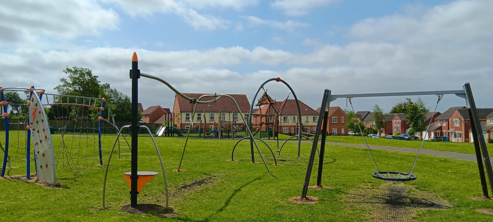 A picture of The Avenue playground with new build houses in the background, built as part of the Revive programme, located next to the Hillside Neighbourhood Community Centre.