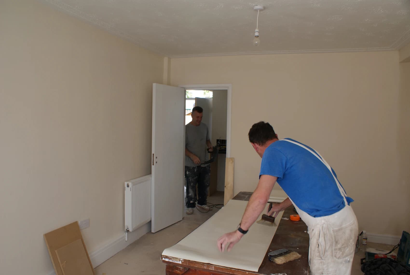 A picture of a man preparing wallpaper to be put up as part of a house renovation.