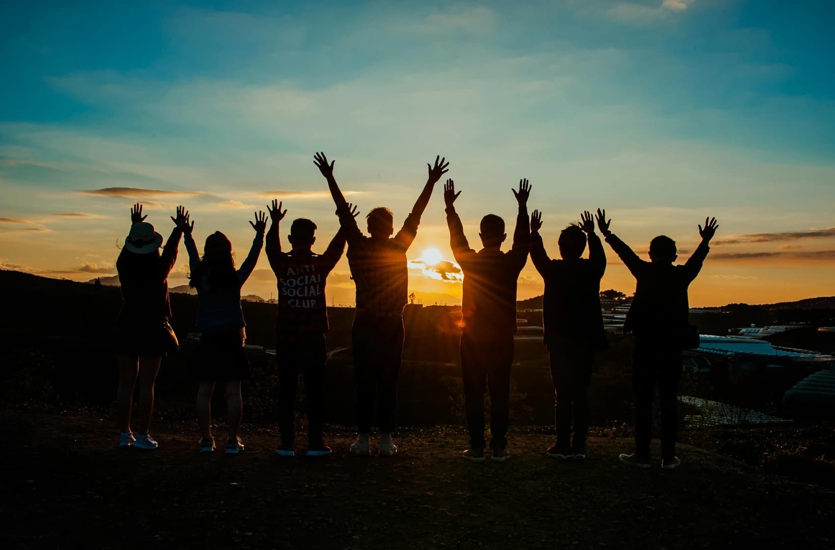 A picture of the community and young people jumping in front of the sunset, representing new opportunity tomorrow.